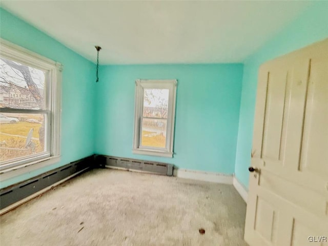 carpeted empty room with a baseboard heating unit