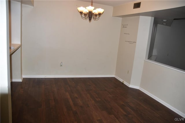 unfurnished room featuring an inviting chandelier and dark wood-type flooring