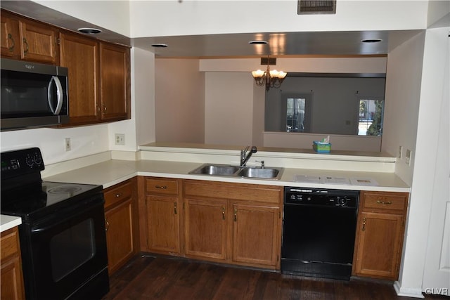 kitchen with a notable chandelier, dark hardwood / wood-style floors, black appliances, kitchen peninsula, and sink