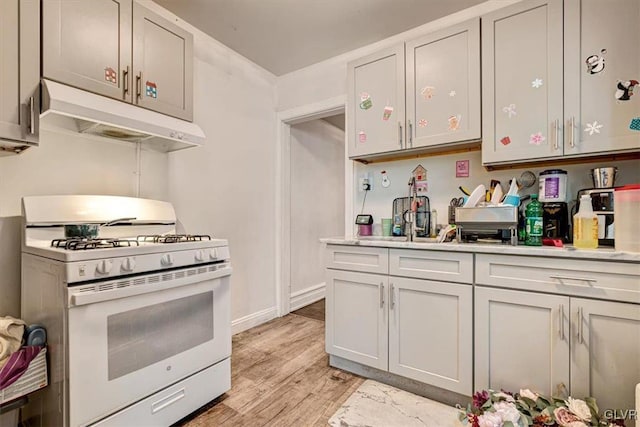 kitchen with white gas stove and light hardwood / wood-style floors