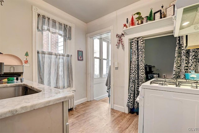 kitchen featuring light stone countertops, stove, ventilation hood, light hardwood / wood-style floors, and white cabinetry