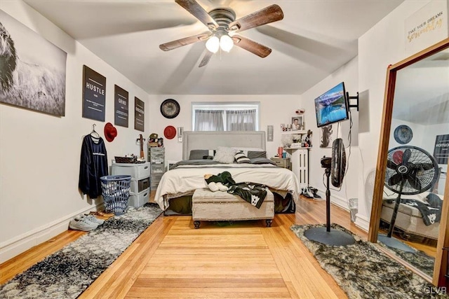 bedroom featuring ceiling fan, radiator heating unit, and wood-type flooring