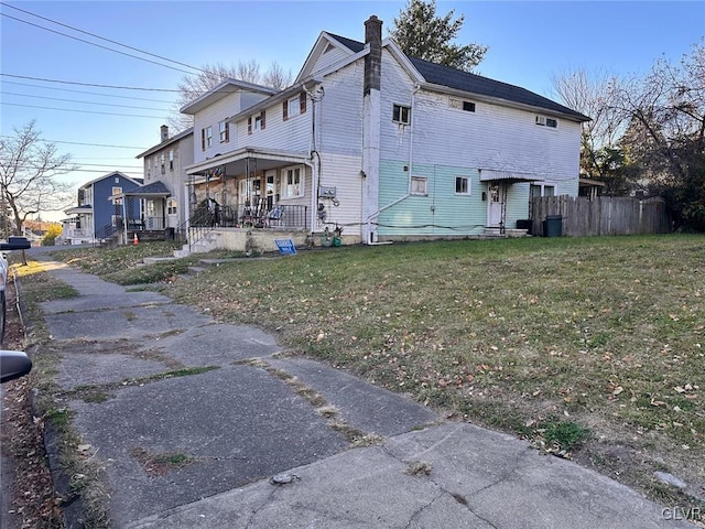 view of side of property with a lawn and covered porch