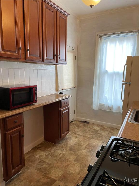 kitchen featuring white refrigerator, stove, built in desk, and sink