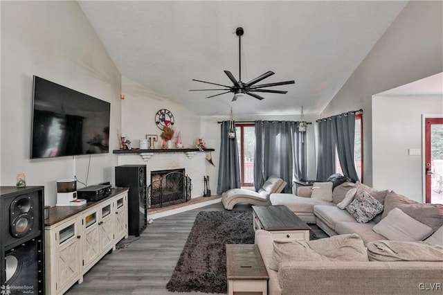 living room featuring a fireplace, ceiling fan, dark wood-type flooring, and vaulted ceiling