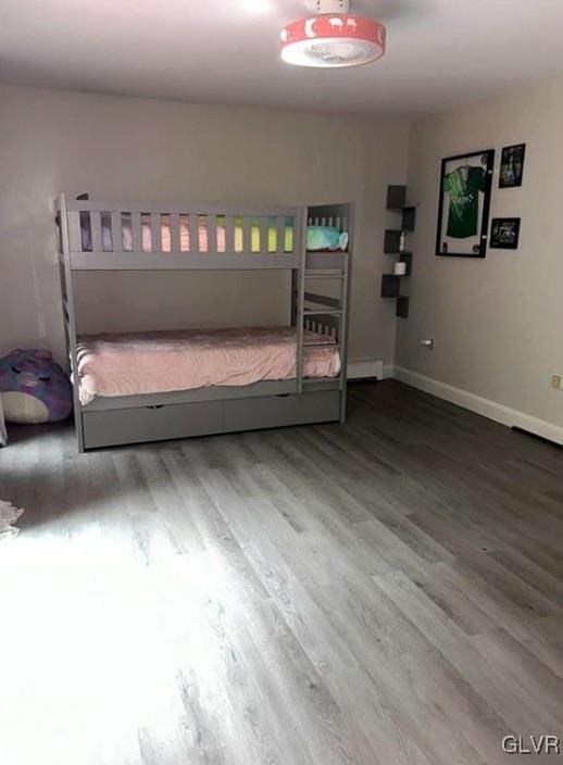 bedroom with baseboard heating and wood-type flooring