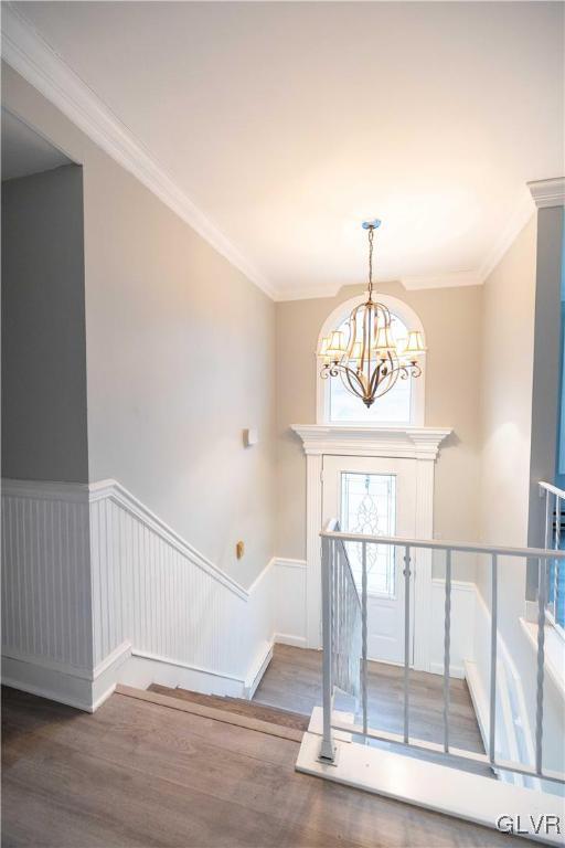 foyer entrance featuring dark hardwood / wood-style flooring, a notable chandelier, and ornamental molding