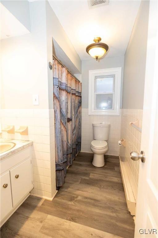 bathroom featuring hardwood / wood-style flooring, vanity, toilet, and tile walls