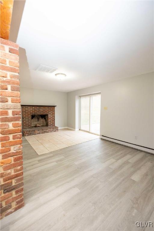 unfurnished living room featuring a fireplace, light hardwood / wood-style floors, and a baseboard heating unit