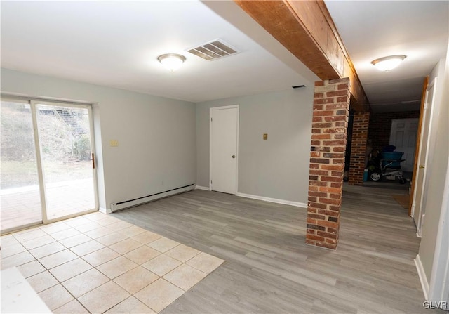 unfurnished room featuring baseboard heating and light hardwood / wood-style floors