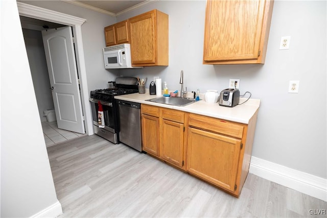 kitchen featuring crown molding, stainless steel appliances, light hardwood / wood-style floors, and sink