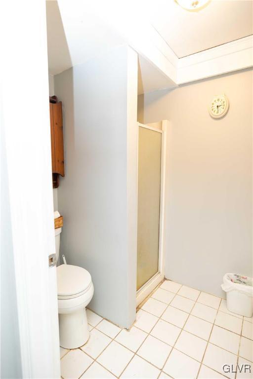 bathroom with toilet, tile patterned floors, and a shower with shower door