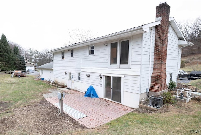 back of house featuring a lawn, central AC unit, and a patio area