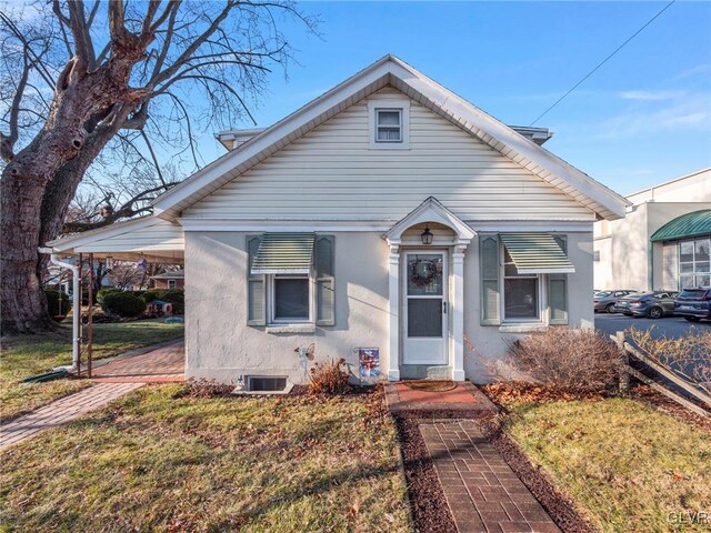 bungalow-style house with a front lawn and a carport