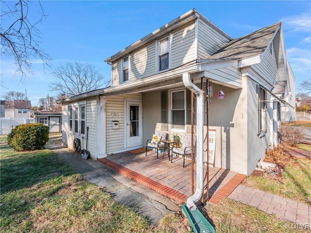 view of front facade with covered porch, a front yard, and stucco siding