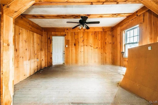 spare room with beamed ceiling, hardwood / wood-style floors, ceiling fan, and wood walls