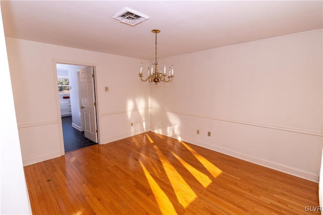 spare room with a chandelier and dark hardwood / wood-style floors