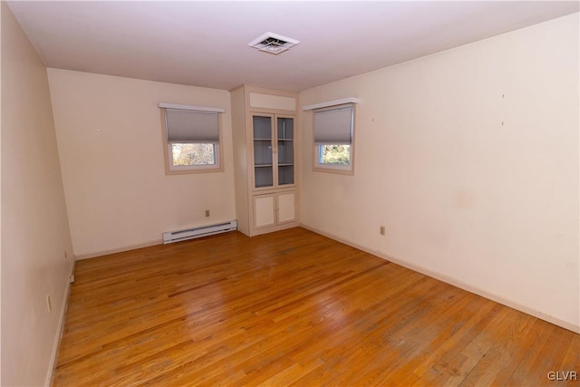 unfurnished room with light wood-type flooring, a wealth of natural light, and a baseboard radiator