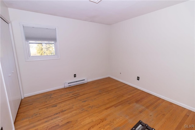 empty room with wood-type flooring and a baseboard radiator