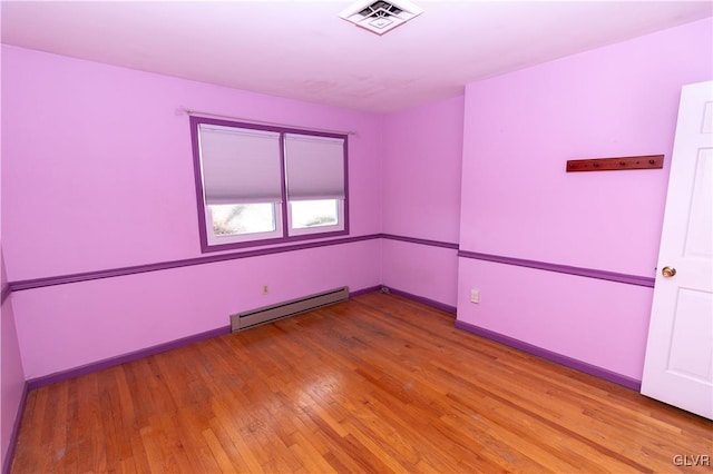 spare room featuring a baseboard radiator and light hardwood / wood-style floors