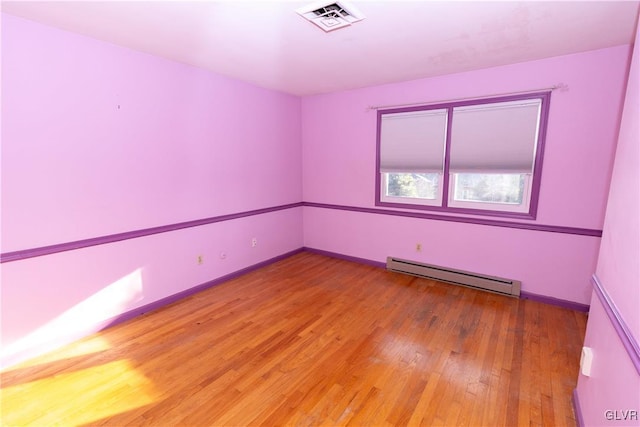 spare room featuring baseboard heating and wood-type flooring