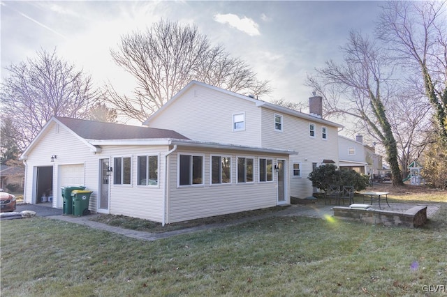 rear view of house featuring a lawn and a garage