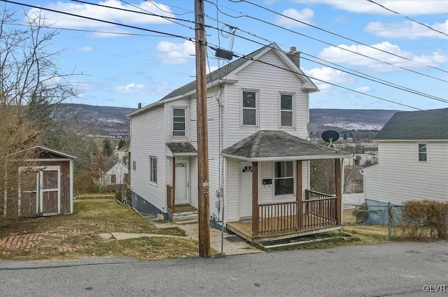 front facade featuring covered porch and a shed