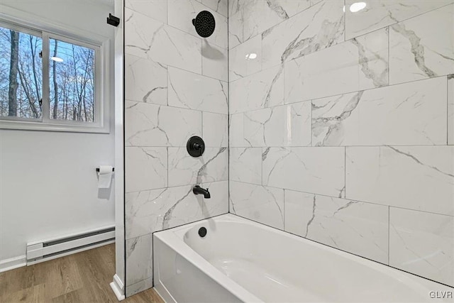 bathroom featuring hardwood / wood-style floors, baseboard heating, and tiled shower / bath