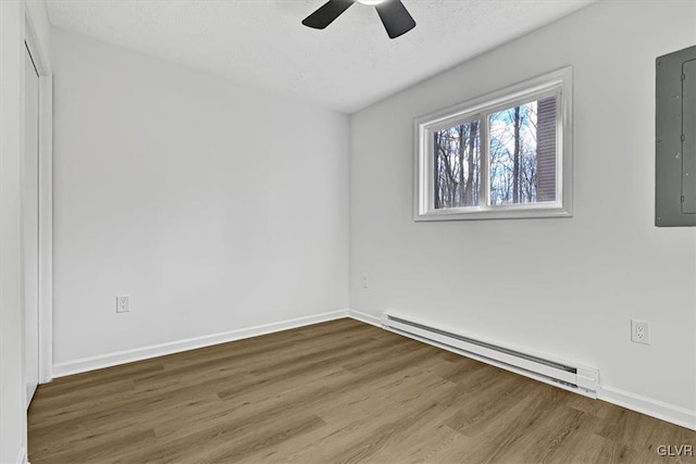 unfurnished room with hardwood / wood-style floors, electric panel, ceiling fan, and a baseboard heating unit