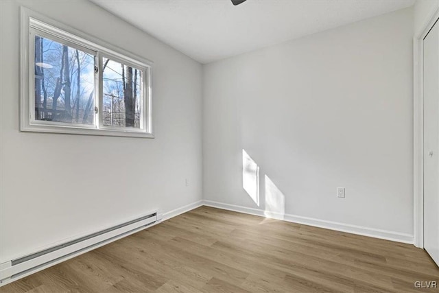 unfurnished room featuring light hardwood / wood-style flooring and a baseboard heating unit