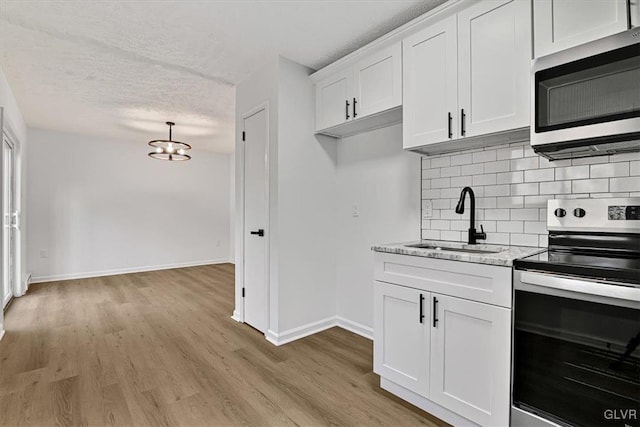 kitchen featuring white cabinets, sink, light stone countertops, a textured ceiling, and stainless steel appliances