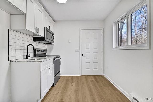 kitchen with decorative backsplash, appliances with stainless steel finishes, sink, a baseboard radiator, and white cabinets