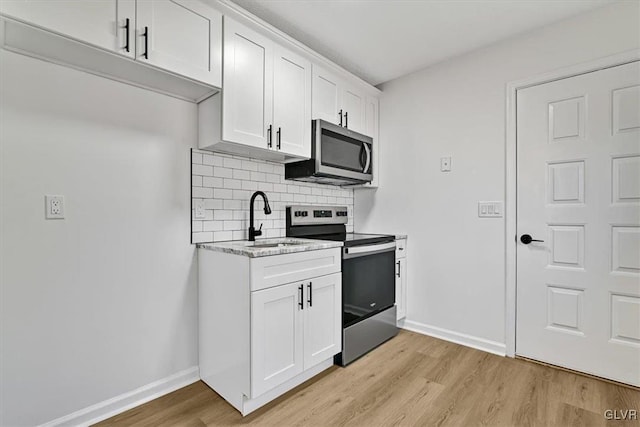 kitchen with white cabinetry, sink, stainless steel appliances, and light hardwood / wood-style floors