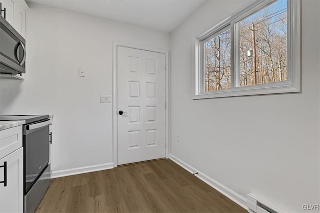 interior space featuring white cabinets, stove, dark hardwood / wood-style floors, and baseboard heating