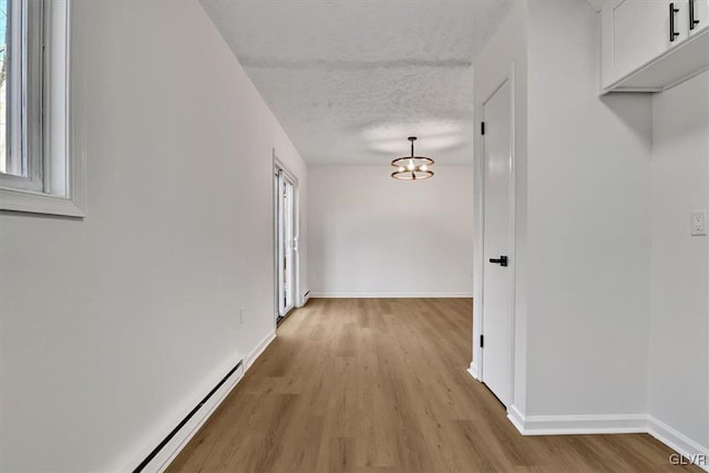 hallway featuring a textured ceiling, an inviting chandelier, a baseboard radiator, and light hardwood / wood-style flooring