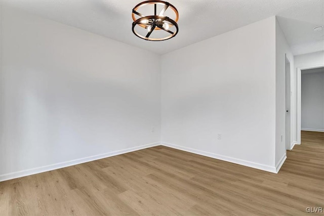 empty room with light hardwood / wood-style floors and an inviting chandelier