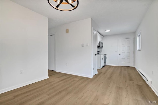 interior space with an inviting chandelier, a baseboard radiator, and light hardwood / wood-style floors