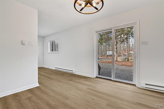 unfurnished dining area featuring hardwood / wood-style flooring, baseboard heating, and an inviting chandelier