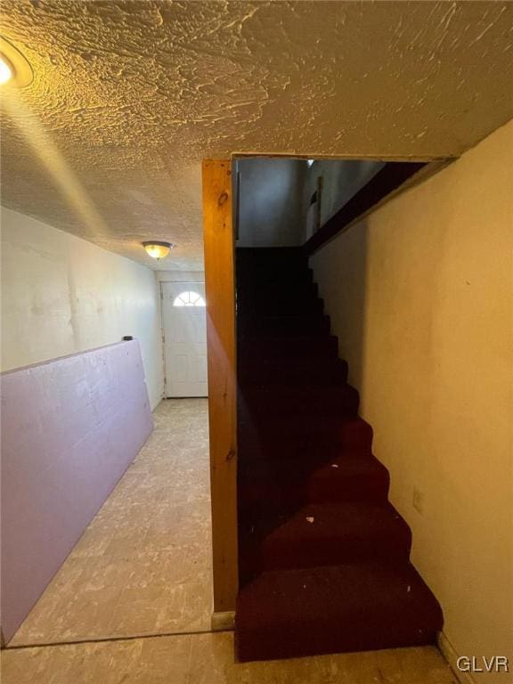 stairs featuring a textured ceiling