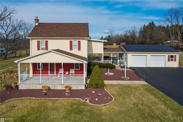 view of front of house with an outbuilding, a porch, a garage, and a front lawn