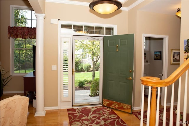 entrance foyer with decorative columns, light hardwood / wood-style flooring, plenty of natural light, and ornamental molding