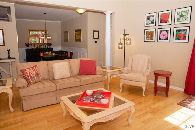 living room featuring decorative columns, hardwood / wood-style flooring, a chandelier, and ornamental molding