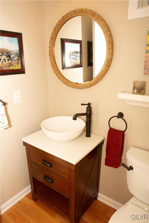 bathroom with hardwood / wood-style floors, vanity, and toilet