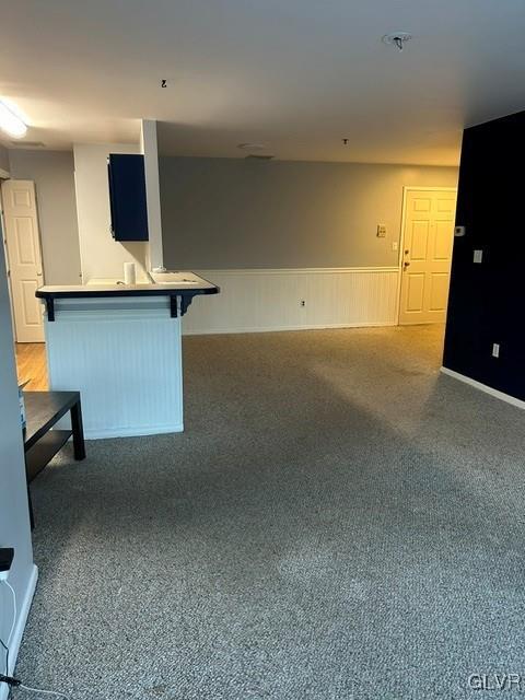 interior space with a breakfast bar, dark carpet, and kitchen peninsula