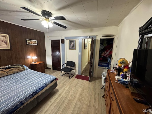 bedroom featuring wooden walls, ceiling fan, and light wood-type flooring