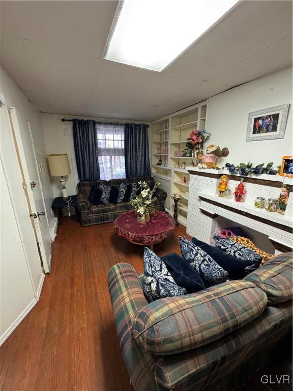 living room with built in shelves and wood-type flooring