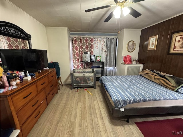 bedroom featuring wood walls, ceiling fan, and light wood-type flooring