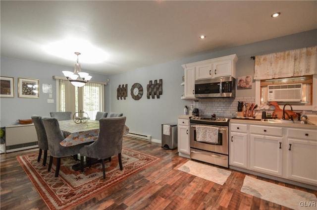 kitchen with appliances with stainless steel finishes, a baseboard heating unit, sink, a notable chandelier, and white cabinetry