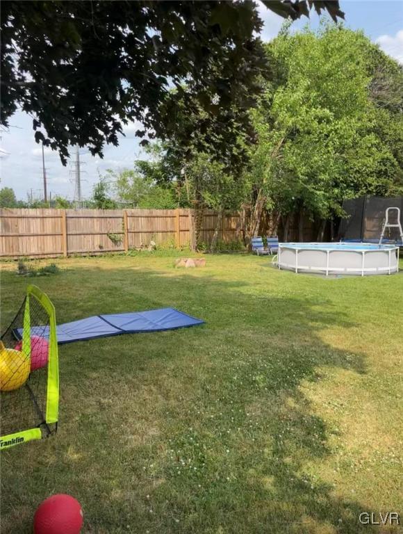 view of yard with a trampoline and a fenced in pool