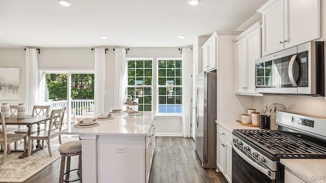 kitchen featuring stainless steel appliances, white cabinets, a center island, and a healthy amount of sunlight